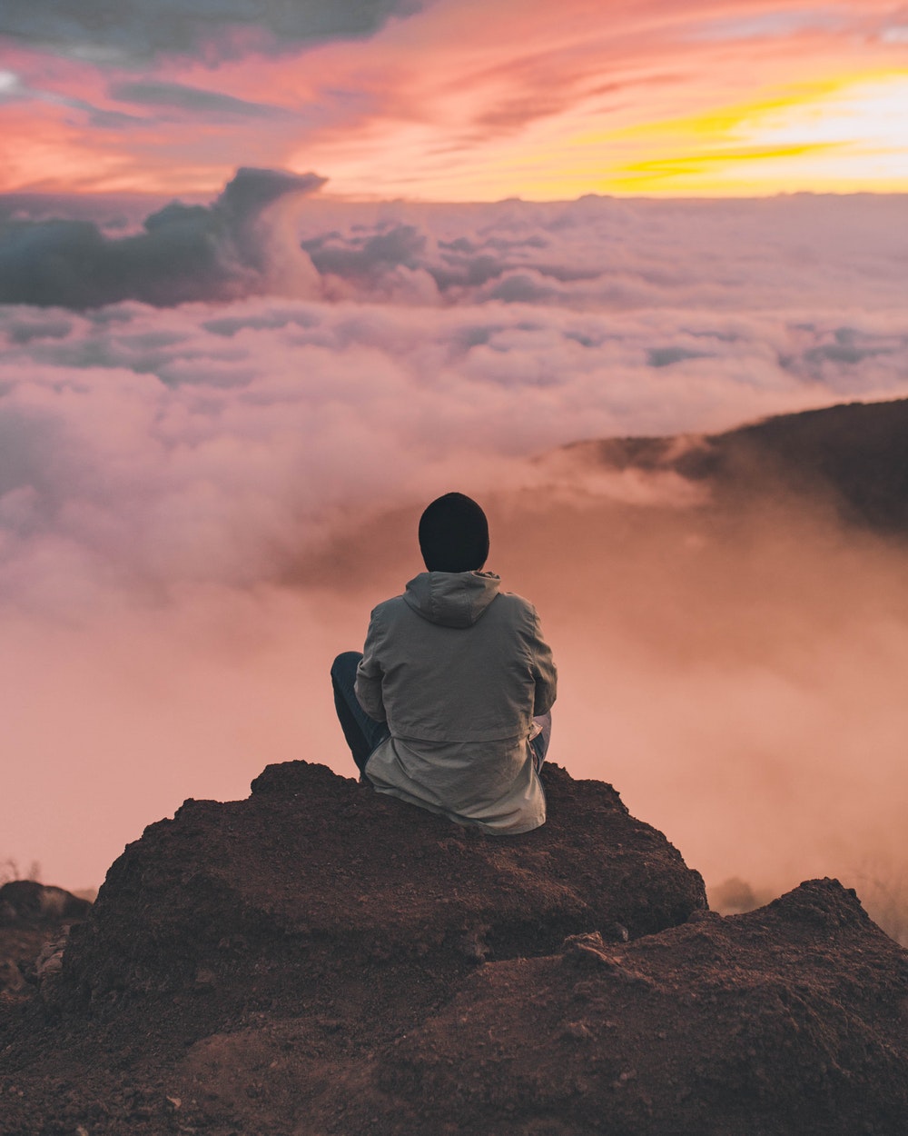 Forgiveness: The Path to Embracing My Lion Heart by Laura Bishop. Photograph of man on cliff looking over clouds and sunset by Ian Stauffer