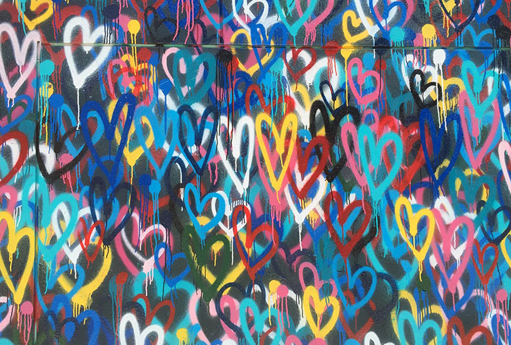 Relationship Myths: Separating from Conventions Frees Us to Enjoy Our Partners Fully by Simone Milasas. Photograph of multicolored hearts spray painted on a wall by Renee Fisher