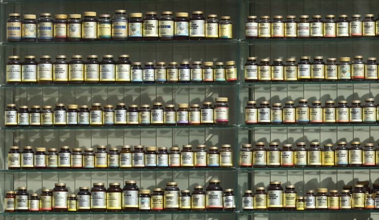Photograph of large wall of bottled supplements. Photograph by Angel Sinigersky.
