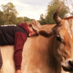 Soul Food: A Journey to Animal Activism by Cerri McQuillan. Photograph of Cerri hugging a cow on the farm