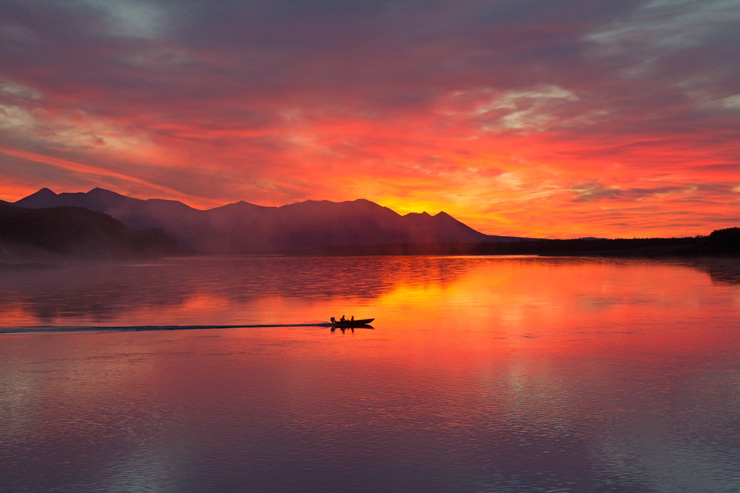 Photograph of a glowing red sunset over a lake