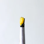 An Artist’s Legacy: It’s Not What We Create, But Rather Who We Become by Hope Koppelman. Photograph of a paintbrush with yellow paint by Ria Alfana