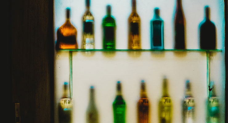Recovering From Alcoholism: Admitting I Have a Problem Was the Hardest Part by Gordon Goad. Photograph of a shelf of liquor by Roberto Roman