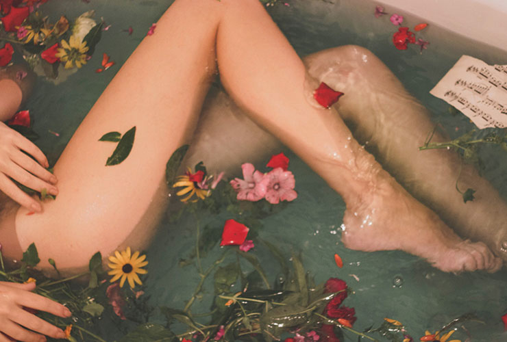 5 Easy & Nurturing Self-Care Treatments You Can Do At Home by Tori Lutz. Photograph of a woman in a bathtub with flower petals by Hanna Postova