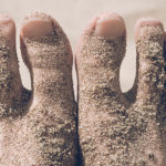 Put Your Best Foot Forward (Literally) by Doug Tumen. Photograph of two sandy feet at the beach by Matthew Wheeler