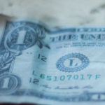 True Abundance: One Man’s Search for (Mindful Money) Meaning by Jim Brown. Photograph of an old dollar bill on a table, by Jack Harner