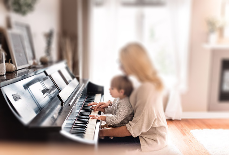Dispelling 3 Myths of Motherhood that Sap Your Joy, Your Work & Your Children by Lauren Marie. Photograph of a mother with her child playing piano by Paige Cody