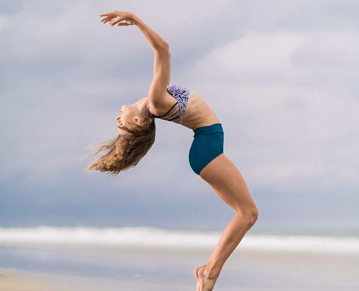 The Exercise Effect: How Fitness Can Boost Your Self-Esteem by Mia Johnson. Photograph of a women doing a backbend yoga pose on the beach by David Hoffman