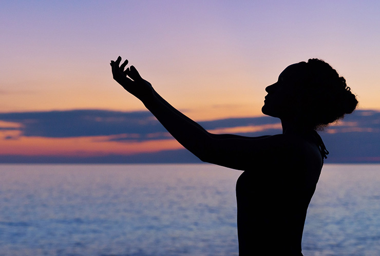 Spiritual Sustainability: So You Want to Change the World? Start Inside by Misti Dian. Photograph of a woman holder her arms up at the beach by William Farlow