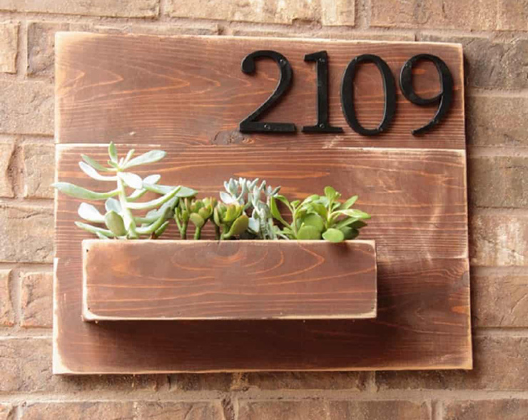 Photograph of a DIY created wooden address sign with succulents in it.