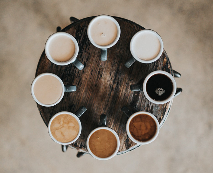 Healthy Guidelines for Consuming Caffeine by Amelia Jones. Photograph of several types of coffee lattes on a table by Nathan Dumlao