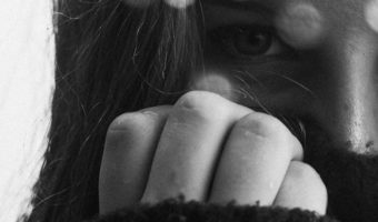 Not In My Backyard: The Reality of Human Trafficking and 5 Steps to End It by Celeste Orr. Photograph of a girl with her hand over her face by Makenna Entrikin