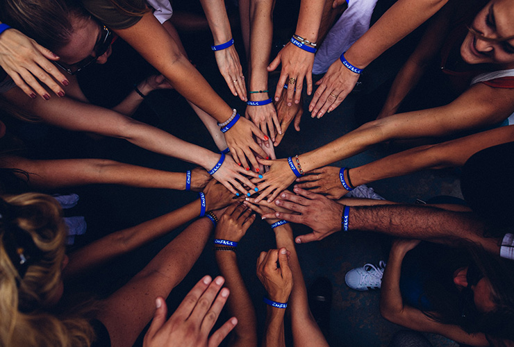 The Importance of Community Service in Shaping the Values of Our Children by Judy Marano. Photograph of a group of people with their hands together by Perry Grone