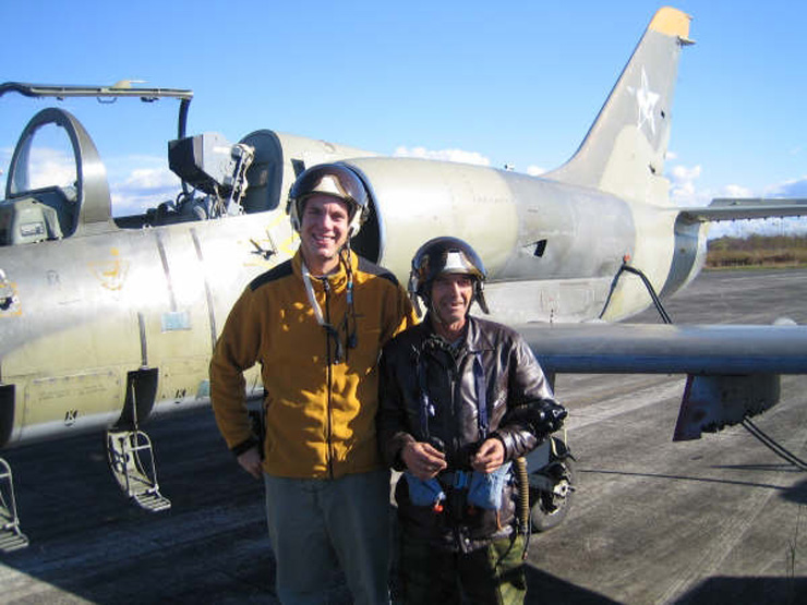 Photograph of Stacy Bare with a fighter Soviet-era jet & pilot.