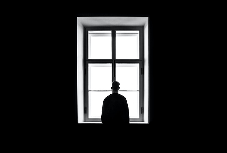 Surviving Coronavirus: Understanding and Discharging Your Distress by Bruce Watkins. Photograph of a man looking out the window by Sasha Freemind