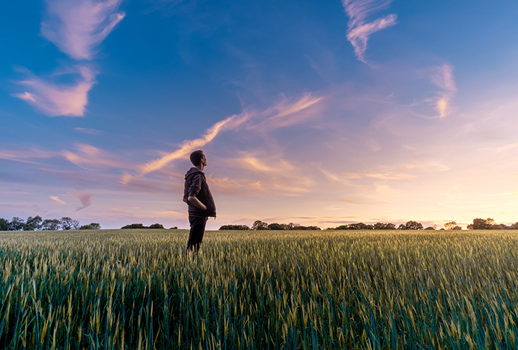 Prepare For Your Future With Mindfulness Practices and Positive Habits by Emily Murphy. Photograph of a man standing in a field looking up at the sky by Benjamin Davis