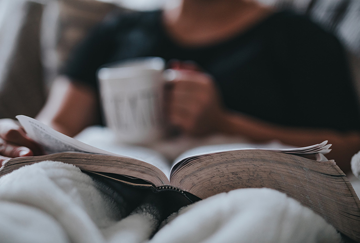 Tired of Just Doing? Embrace Inaction as an Opportunity to Realign Your Goals by Mirra Jensen. Photograph by of a man lying in bed reading by Nathan Dumlao.