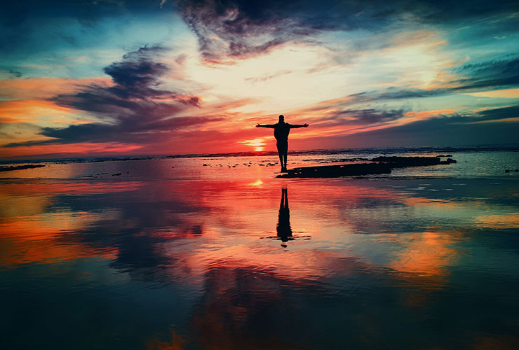 How to Take Control of Your Life and Begin Living Consciously by Damien Justus. Photograph of a man standing in the water during a sunset by Mohammed Nohassi