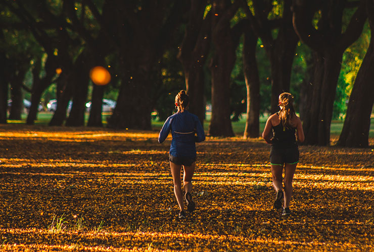 How to Create a Great Outdoor Workout by Sarah Peterson. Photograph of two women running through a park by Geronimo Giqueaux