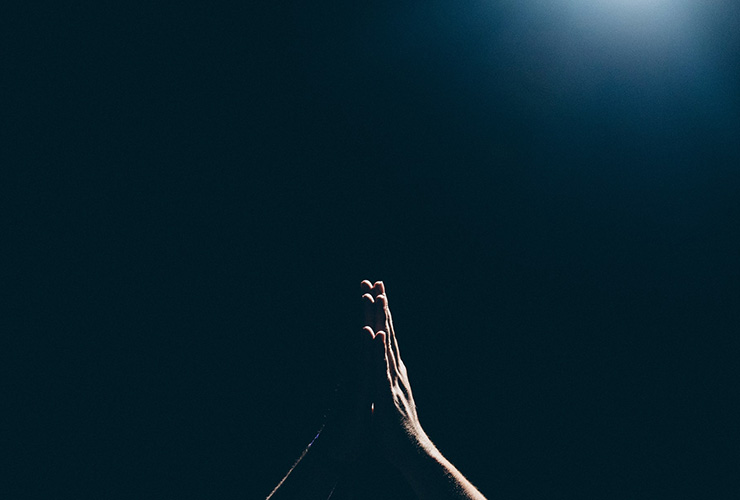 The Sacred Purpose of Human Life by Barbara Ann Briggs. Photograph of hands, praying in the dark by Amaury Gutierrez