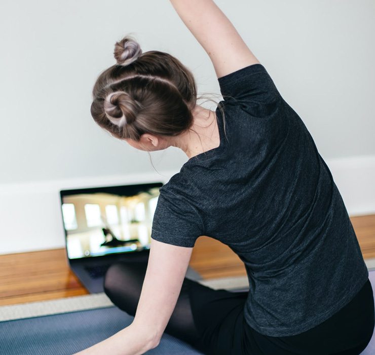 Redefining Fitness and Community in a Post-Covid World, by Amaya Weddle. Photograph of a women doing an online yoga class by Kari Shea