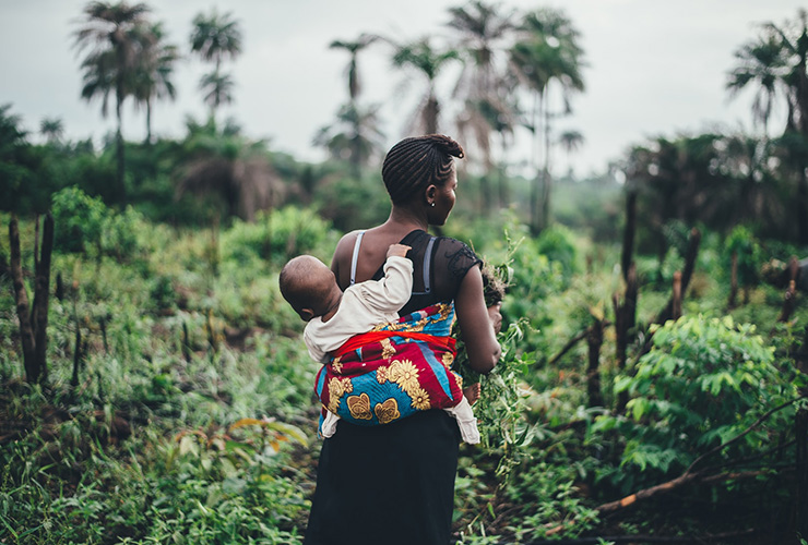 The Women of the Village: How They Saved Us Again by Laura Milligan. Photograph of an African women with a baby on her back by Annie Spratt