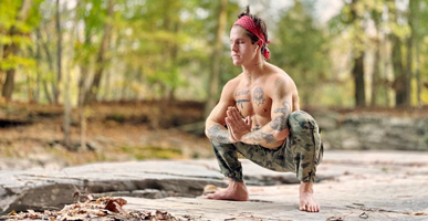 Best Self Yoga: Inner Power Warrior Flow by Carter Miles. Photograph of Carter in malasana, by a river bank.