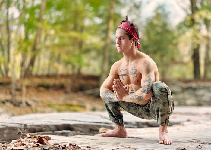 Best Self Yoga: Inner Power Warrior Flow by Carter Miles. Photograph of Carter in malasana, by a river bank.