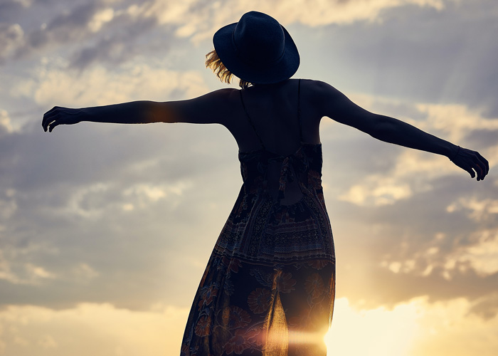 7 Ways to Release Grief from Your Body by Joni Sense. Photograph of a woman's silhouette dancing in the sunset by Darius Bashar