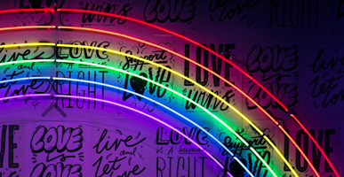 HLGBTQ+: When Will the Discussion End? by Nejoud Al-Yagout. Photograph of a rainbow neon sign over a love wall by Jason Leung