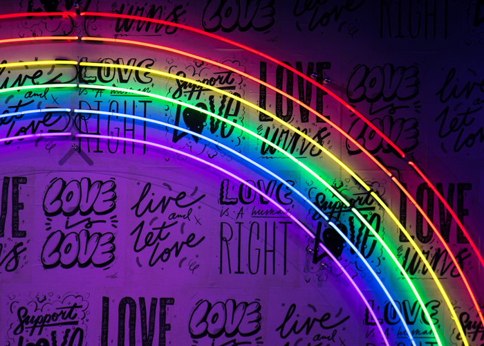 HLGBTQ+: When Will the Discussion End? by Nejoud Al-Yagout. Photograph of a rainbow neon sign over a love wall by Jason Leung