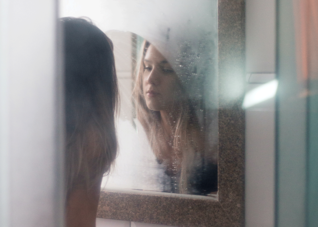 Healing from Body Shame: A Guide to Radical Self-love by Juliette Karaman. Photograph of a woman looking at herself in the mirror by Vinicius Amano