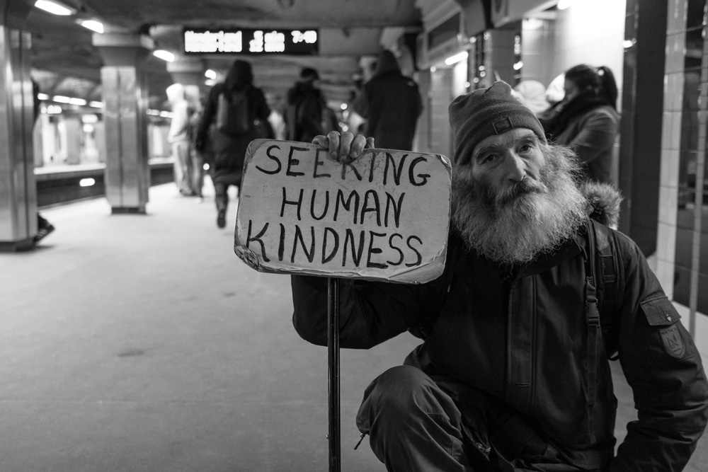 The Crisis of Homelessness and a Call for Love, by Barbara Briggs. Photograph of homeless man with sign by Matt Collamer