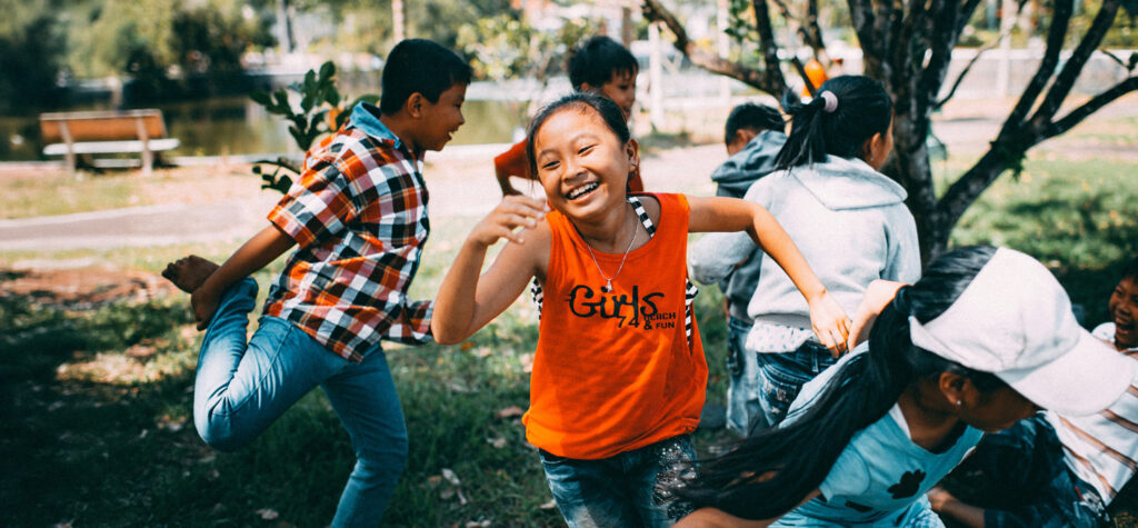 Raising Resilient, Responsible, Happy Kids Through Asset-Heavy Moments, by Kathleen P. Allen. Photograph of happy kids playing outside by Mi Pham