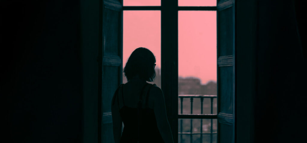A woman staring out a window, surprised by a sudden revelation in her life