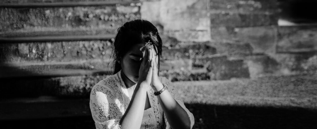 Young woman praying, extending blessings. Photograph by Polina Kuzovkova.