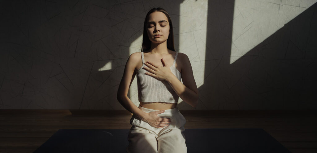 Woman with hand on chest and abdomen doing breathwork